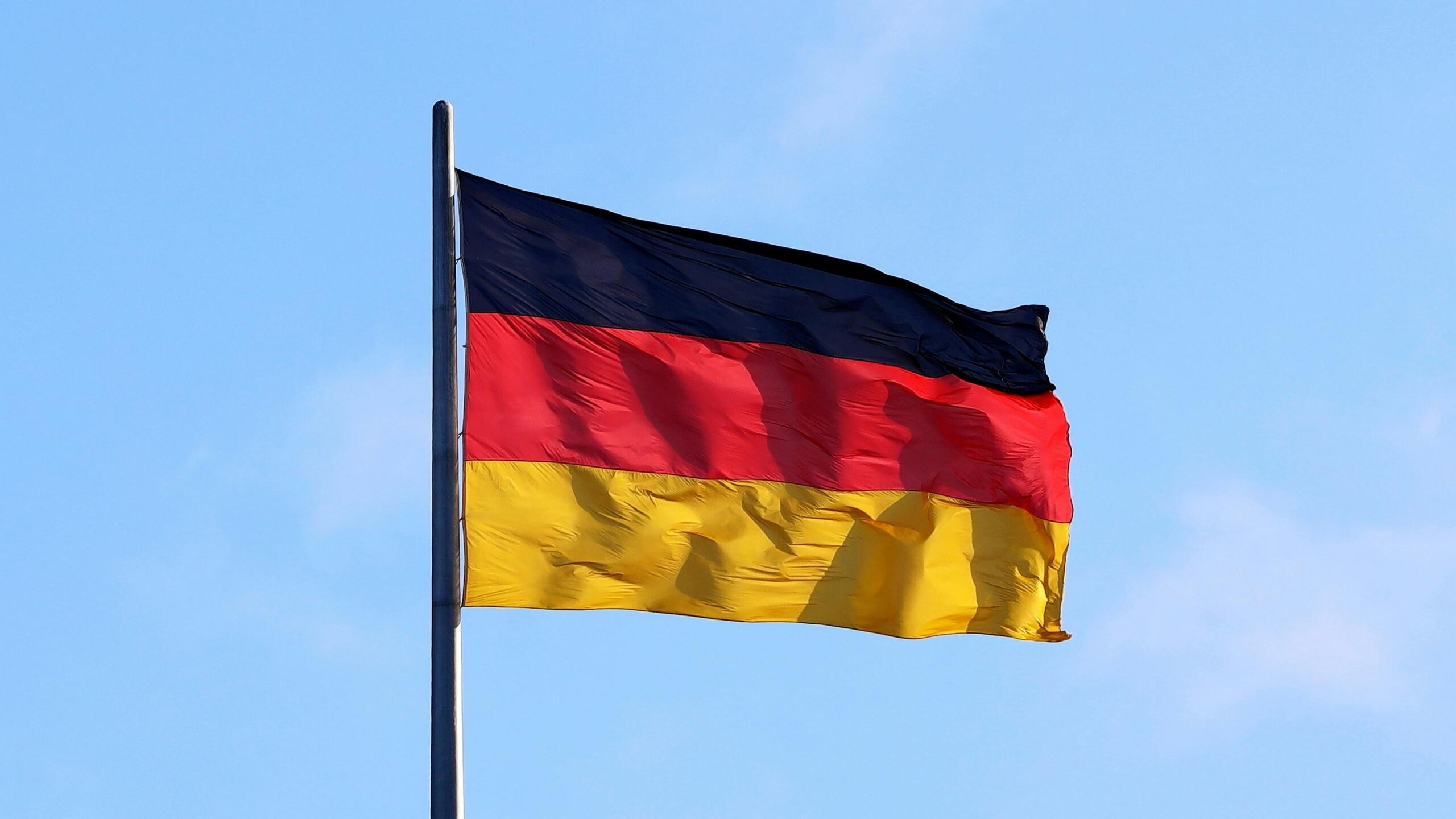 The flag of Germany set against a blue sky.