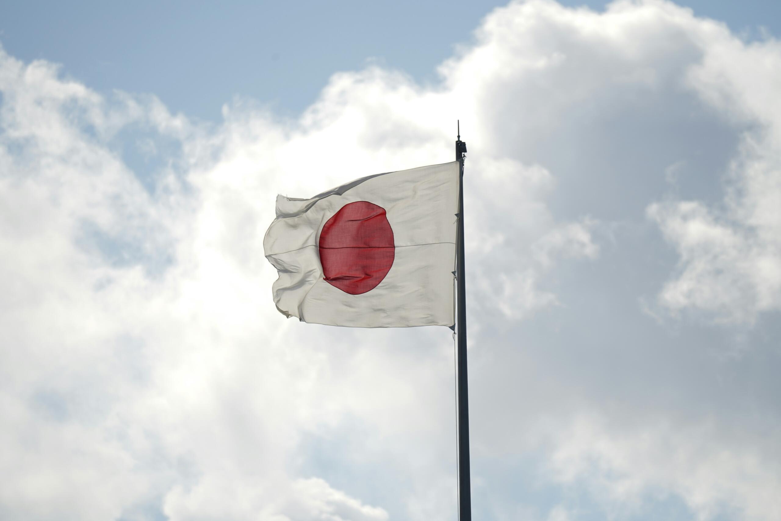 The flag of Japan set against a background with clouds.