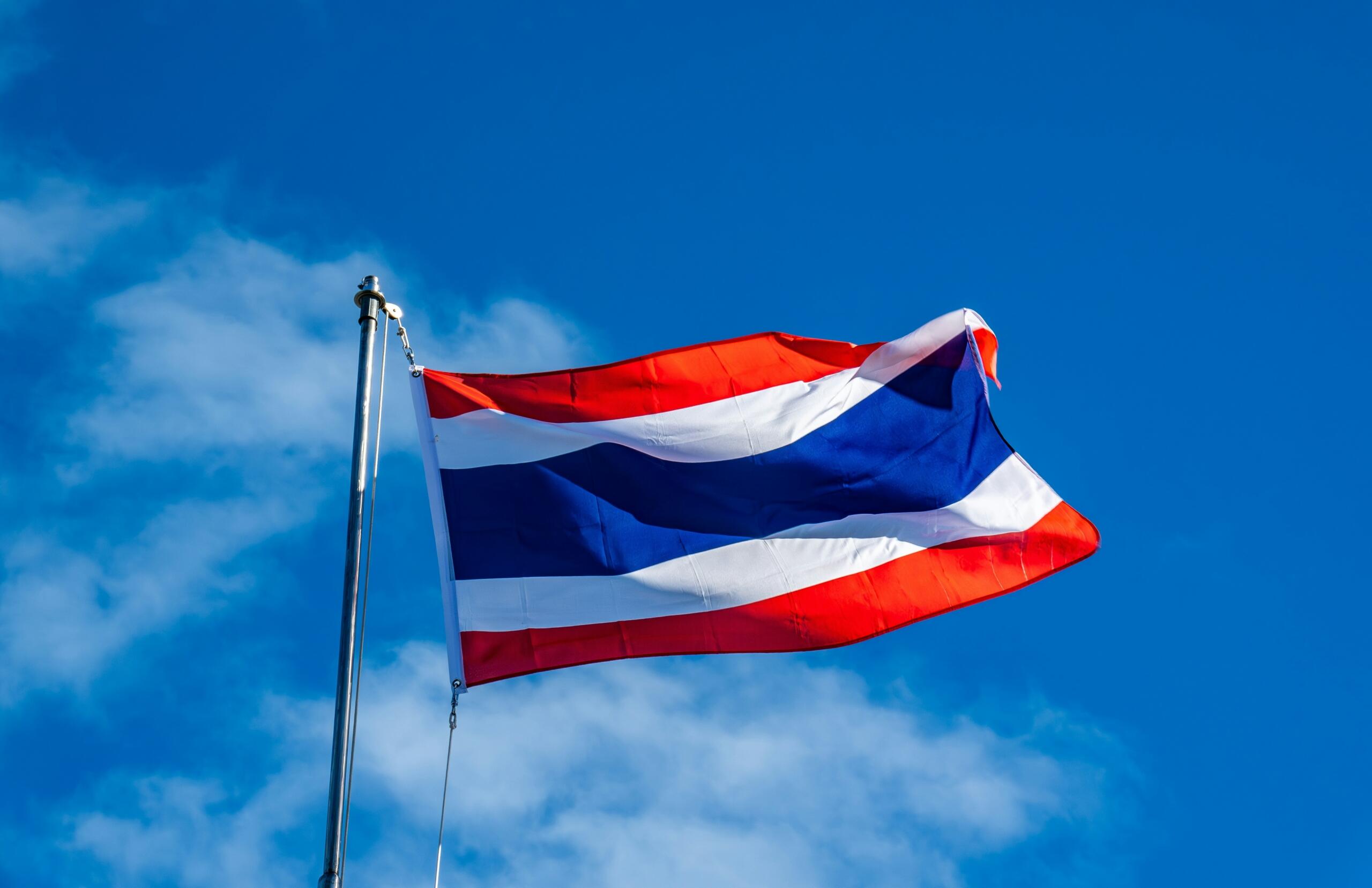 The flag of Thailand against a blue sky.