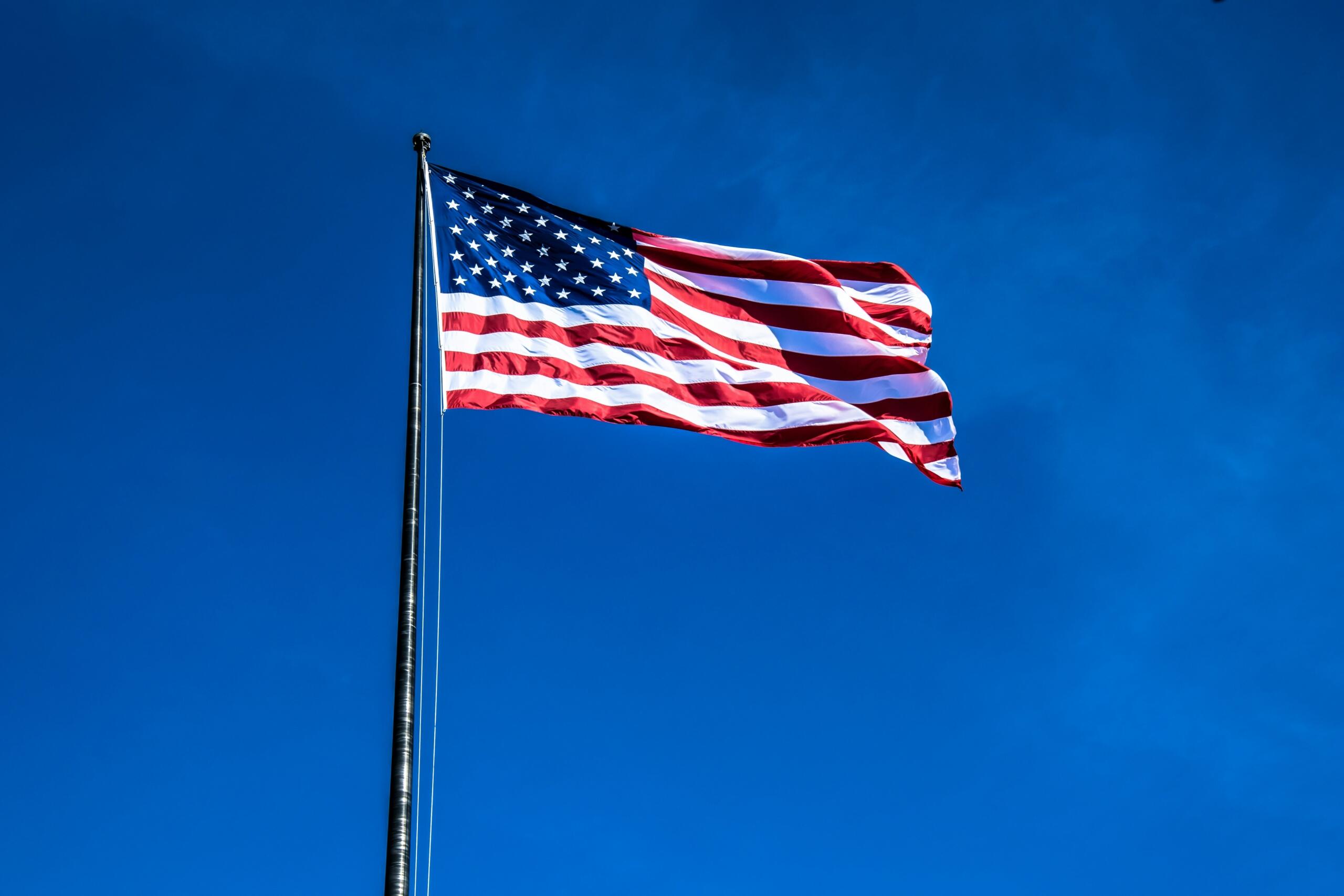 The flag of the United States against a blue sky.
