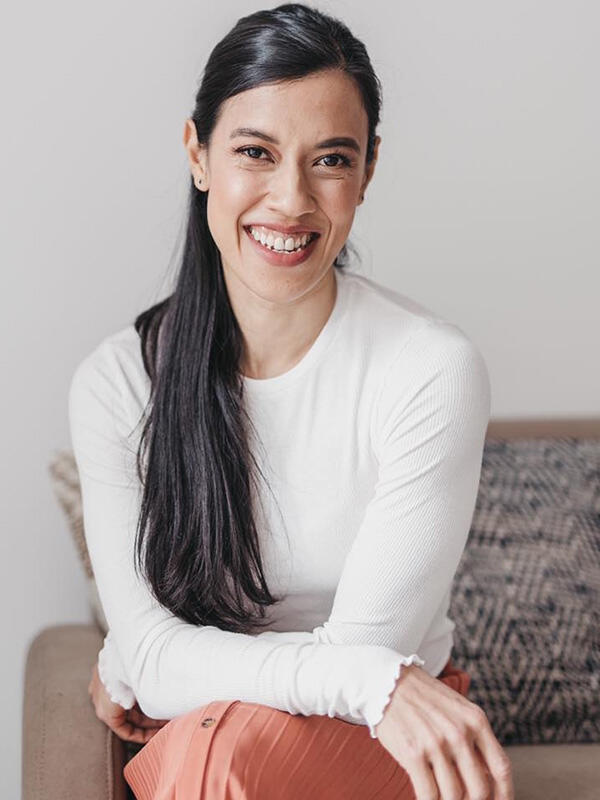 Datuk Nicol Ann David in a white top and peach skirt, sitting and smiling at the camera.