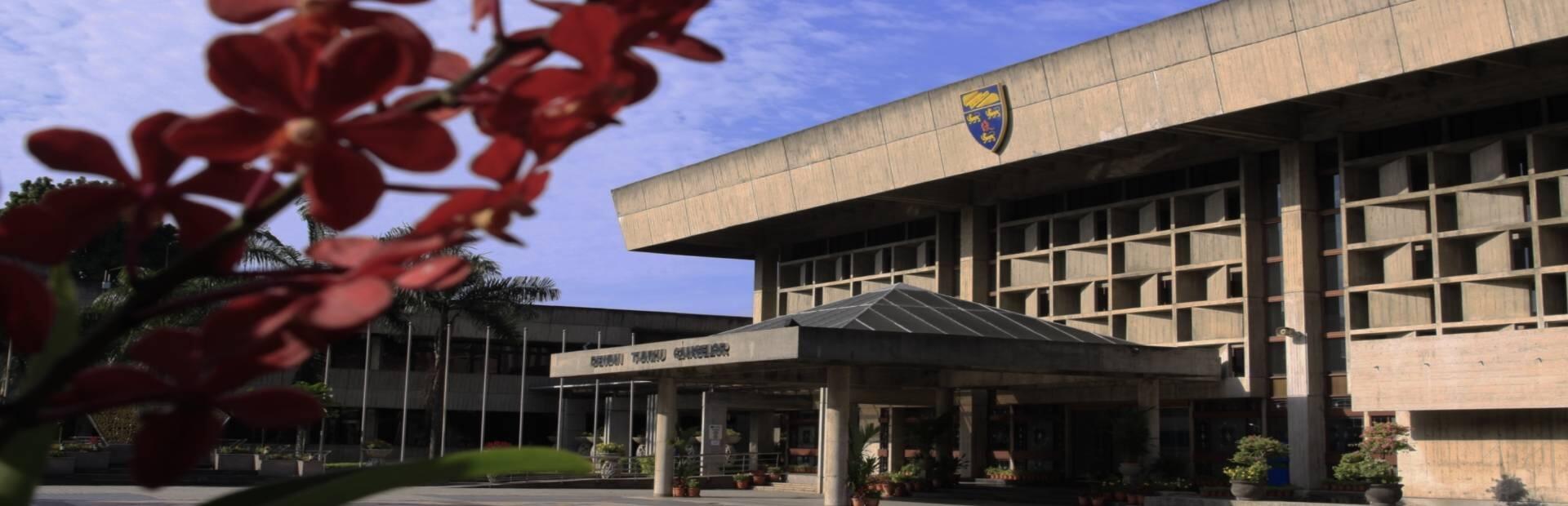 A picture of a Universiti Malaya building with the school's crest.