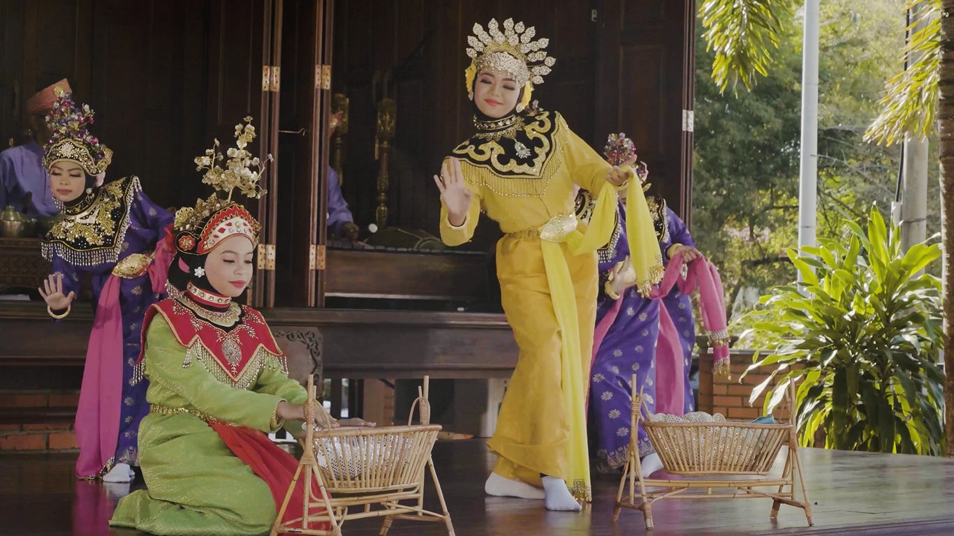 Joget Gamelan Dance - Dancers in vibrant traditional costumes perform gracefully on stage, with a focus on a performer in yellow. The scene is lively and cultural.