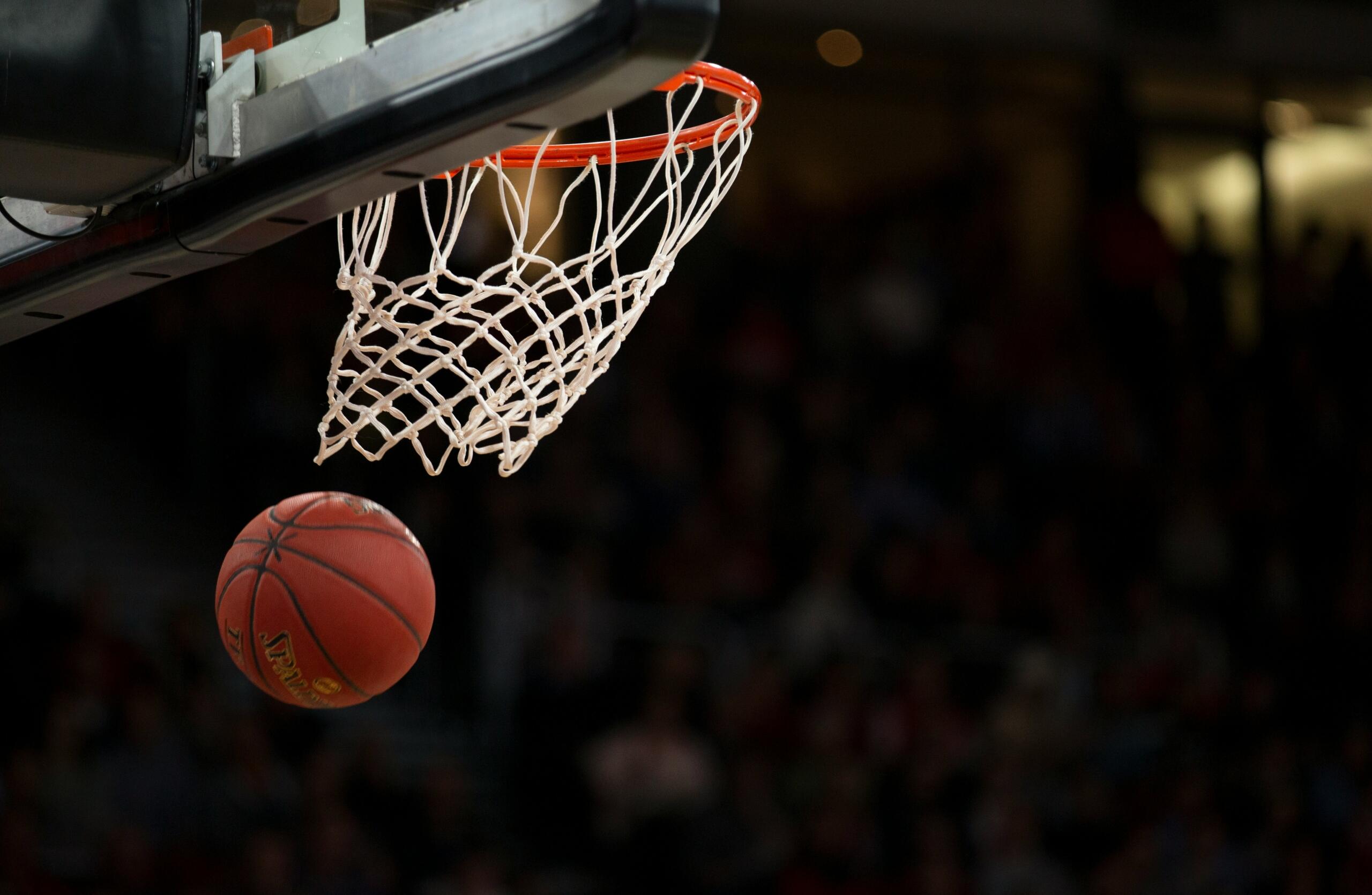 A basketball is successfully lodged in the net of a basketball hoop, showcasing a perfect shot.