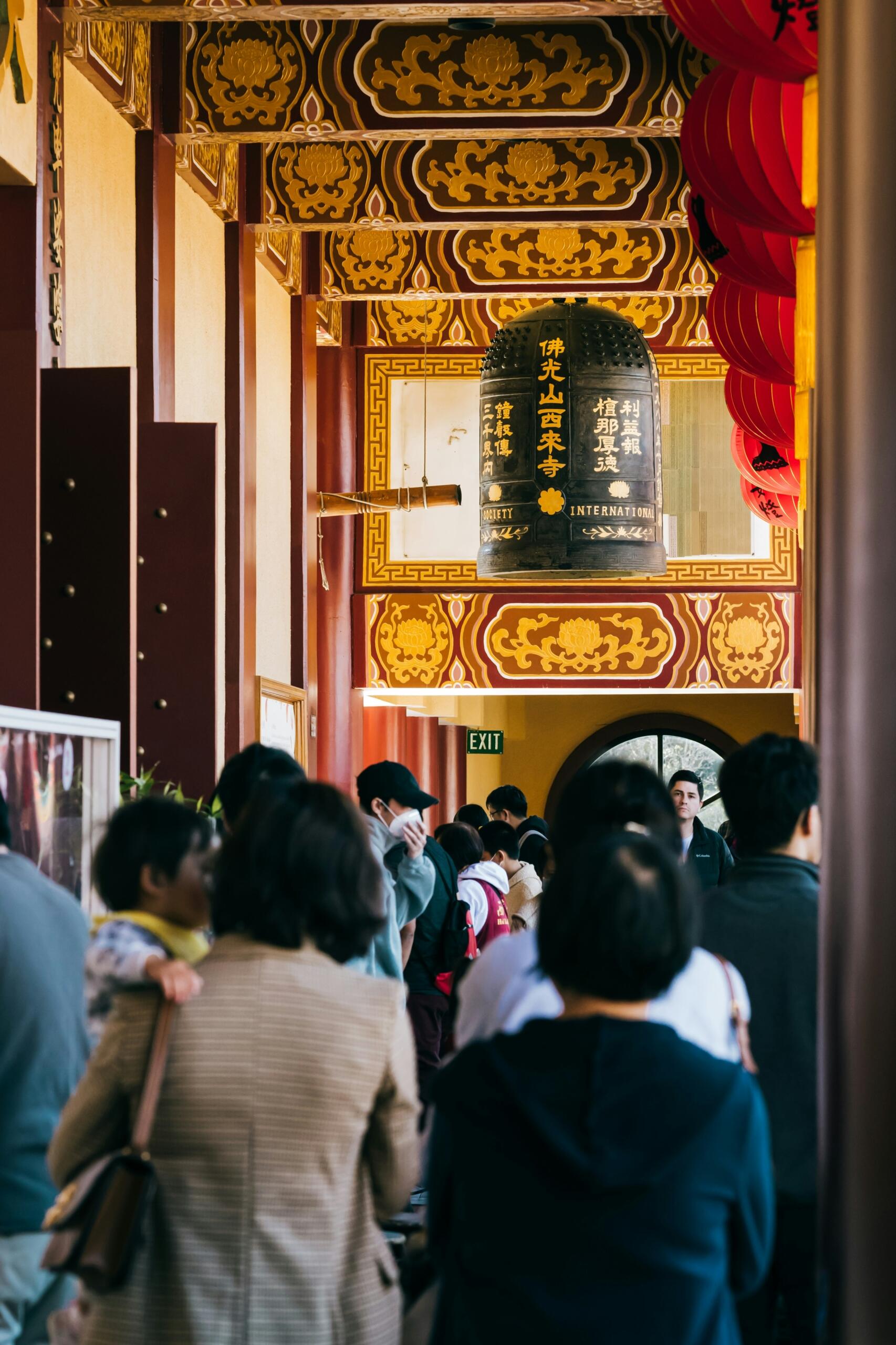 Groups of people moving around in a building adorned with Chinese characters.