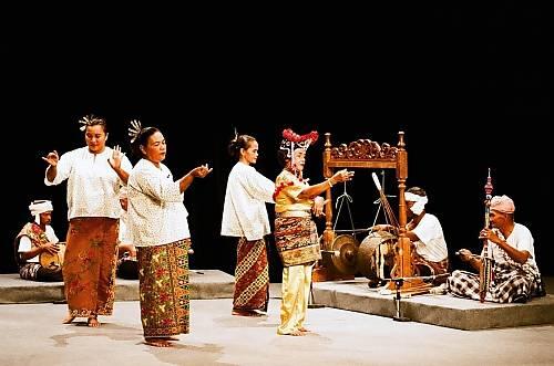 Mak Yong dancers in vibrant attires dancing gracefully beside musicians playing percussion and string instruments onstage.