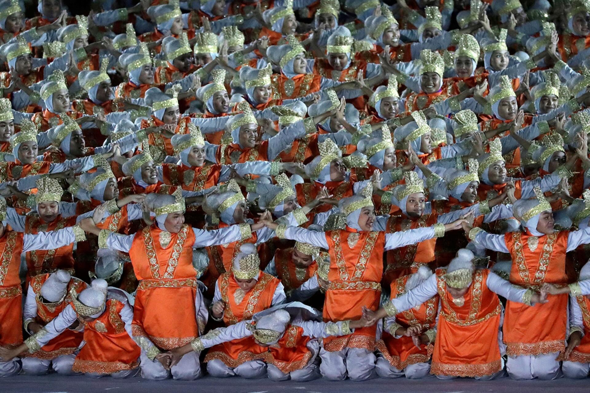 A group of individuals dressed in vibrant orange and white costumes, showcasing a festive and lively atmosphere.