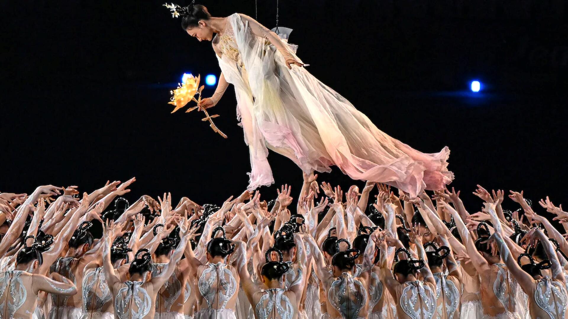 A group of people lifts a woman in a white dress, showcasing a moment of joy and celebration.