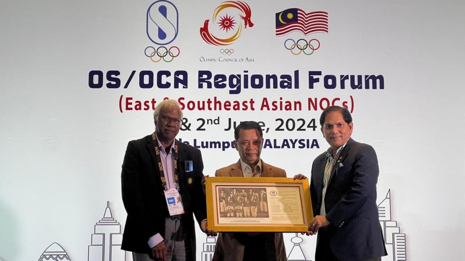 Three men holding a framed photo at the OS/OCA Regional Forum for East & Southeast Asian NOCs, Kuala Lumpur, Malaysia, June 2024.