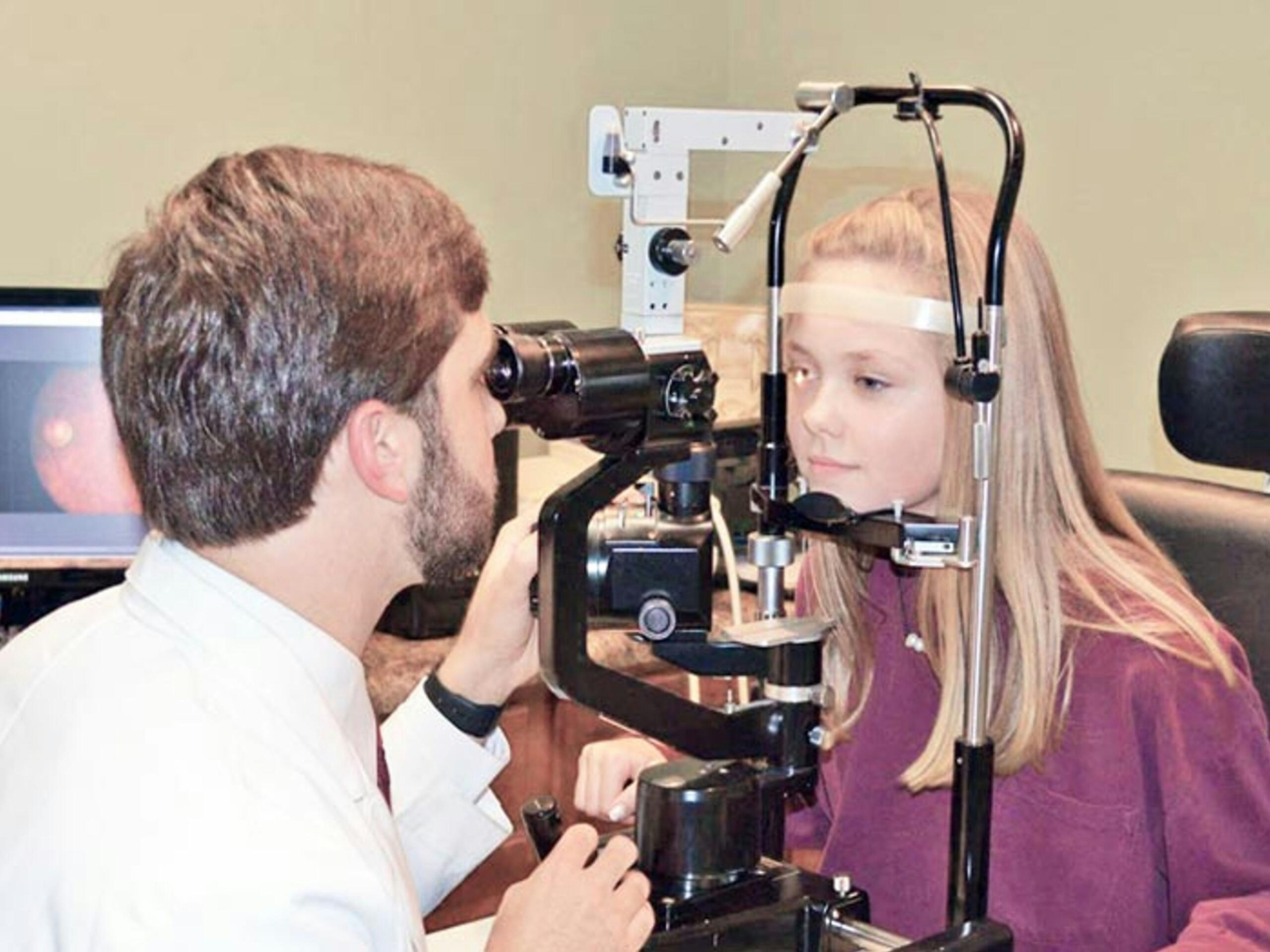 An eye specialist performing an eye test with a young patient.
