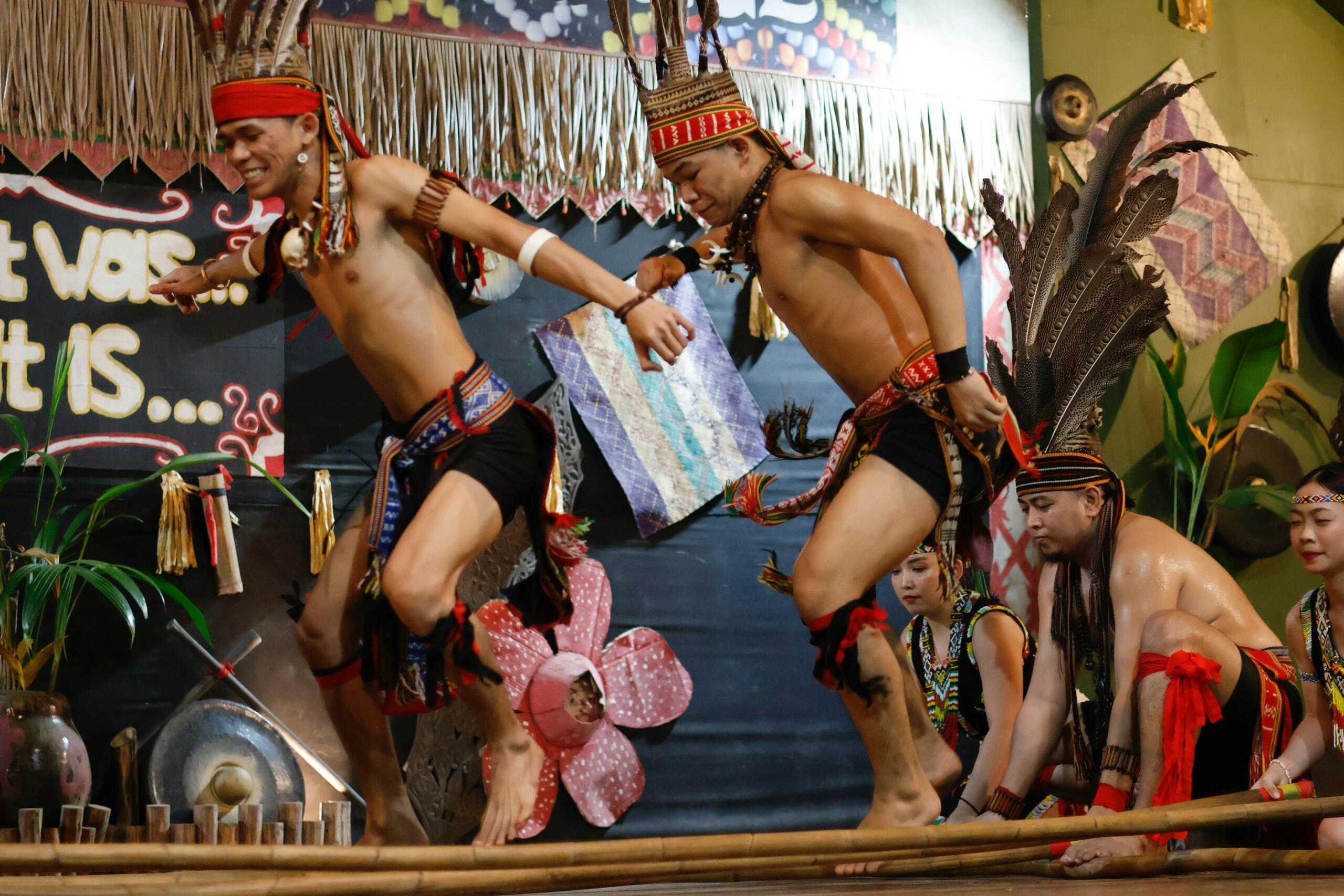 Two dancers jump over bamboo sticks in a Magunatip dance performance.