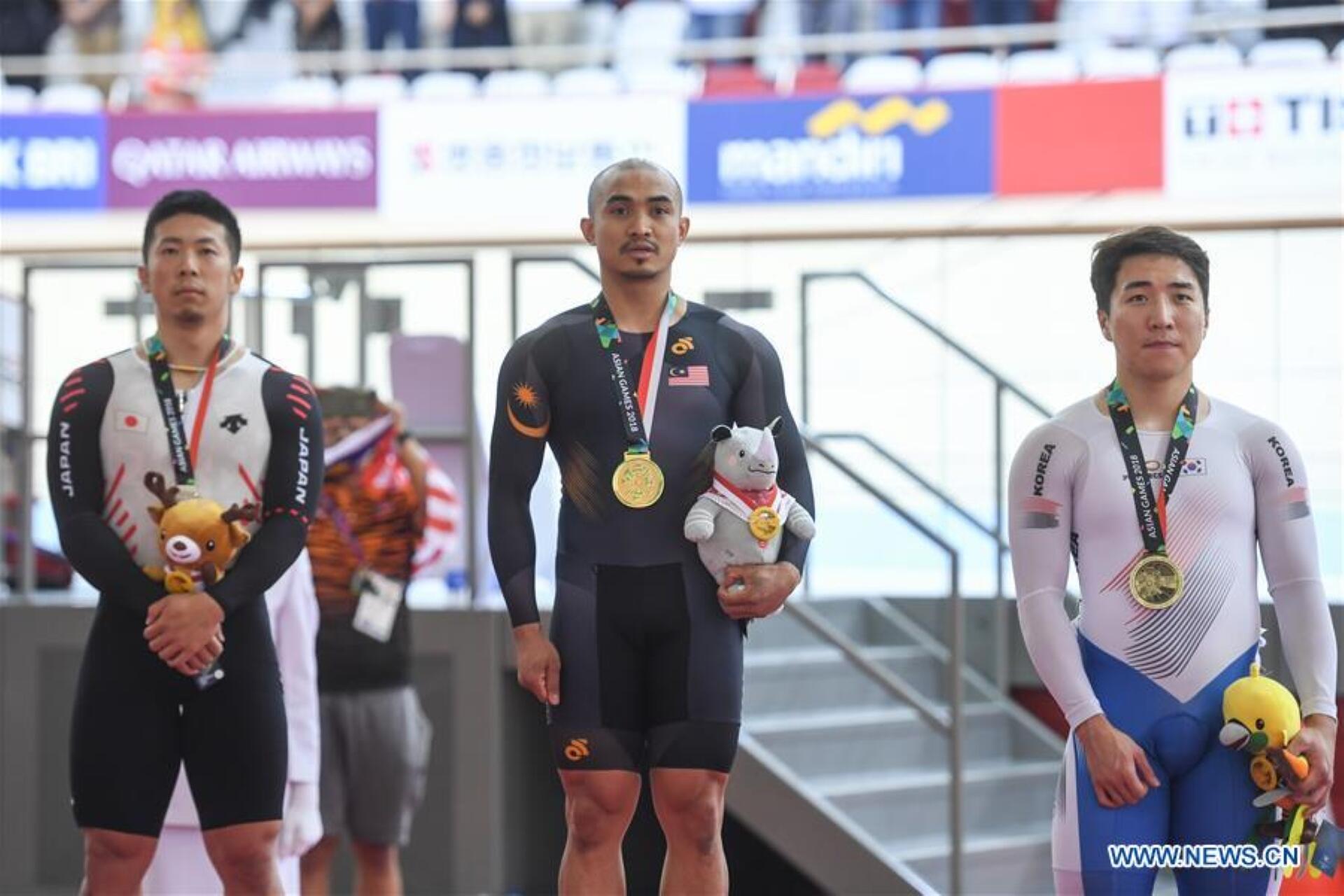Three medalists stand on a podium, celebrating their achievements in a competitive sports event.