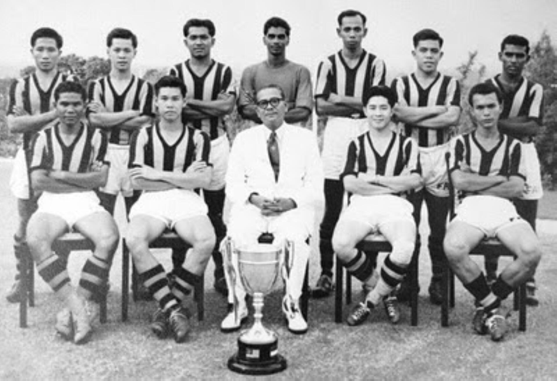 A black and white photo of a team proudly holding a trophy, celebrating their victory together.