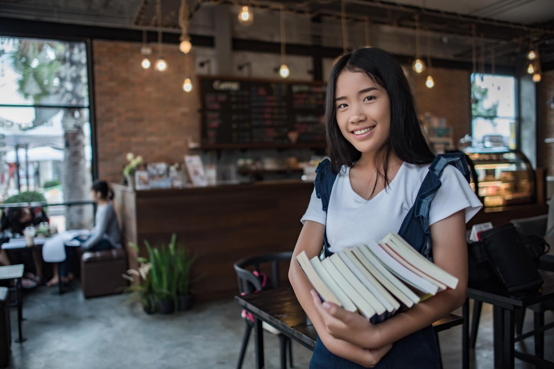A motivated student holding books in a study space, symbolising effective preparation strategies for how to score pengajian am stpm.