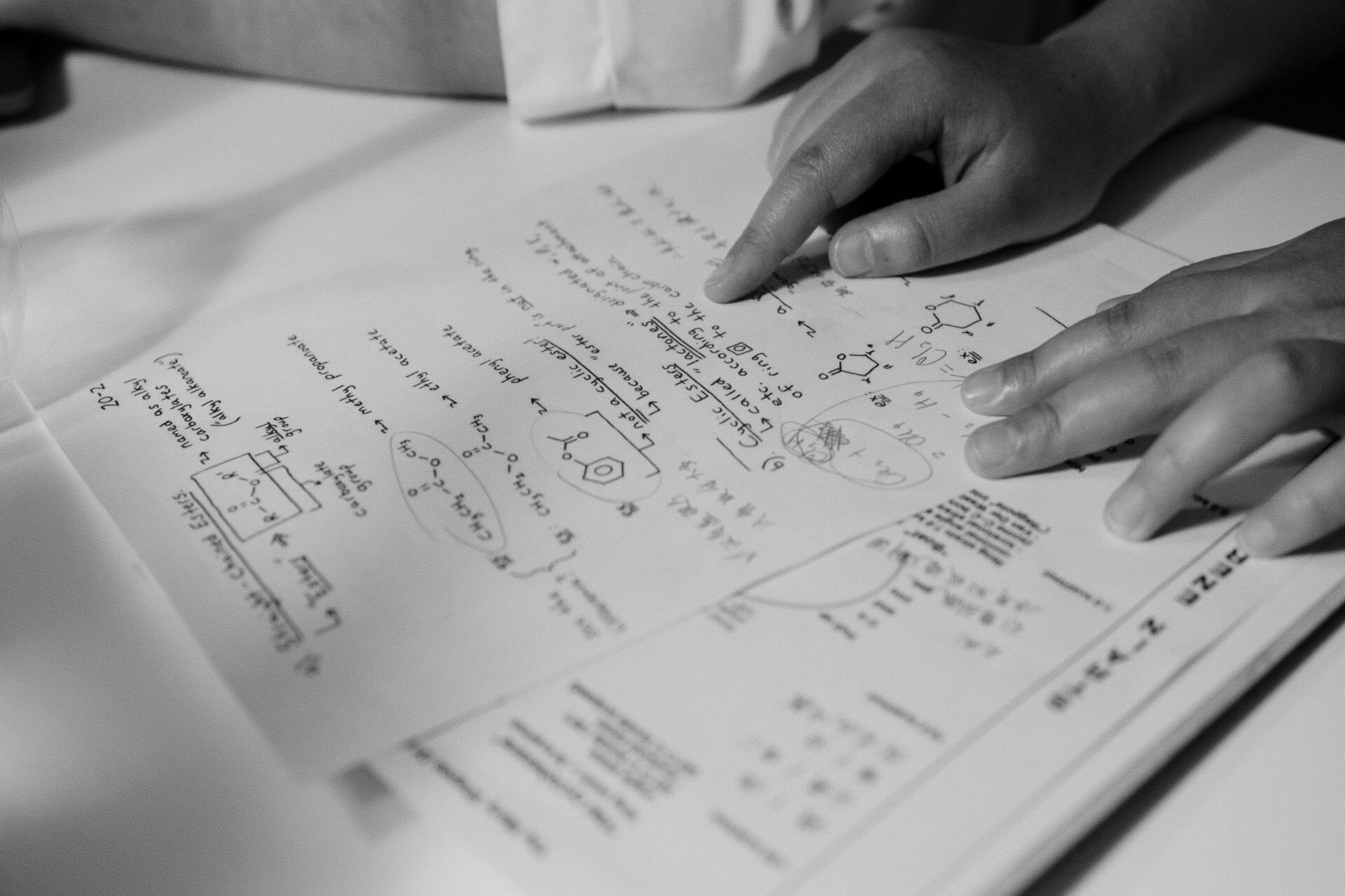 Student reviewing a Chemistry worksheet containing chemical formulas, reaction mechanisms, and exam-style questions.