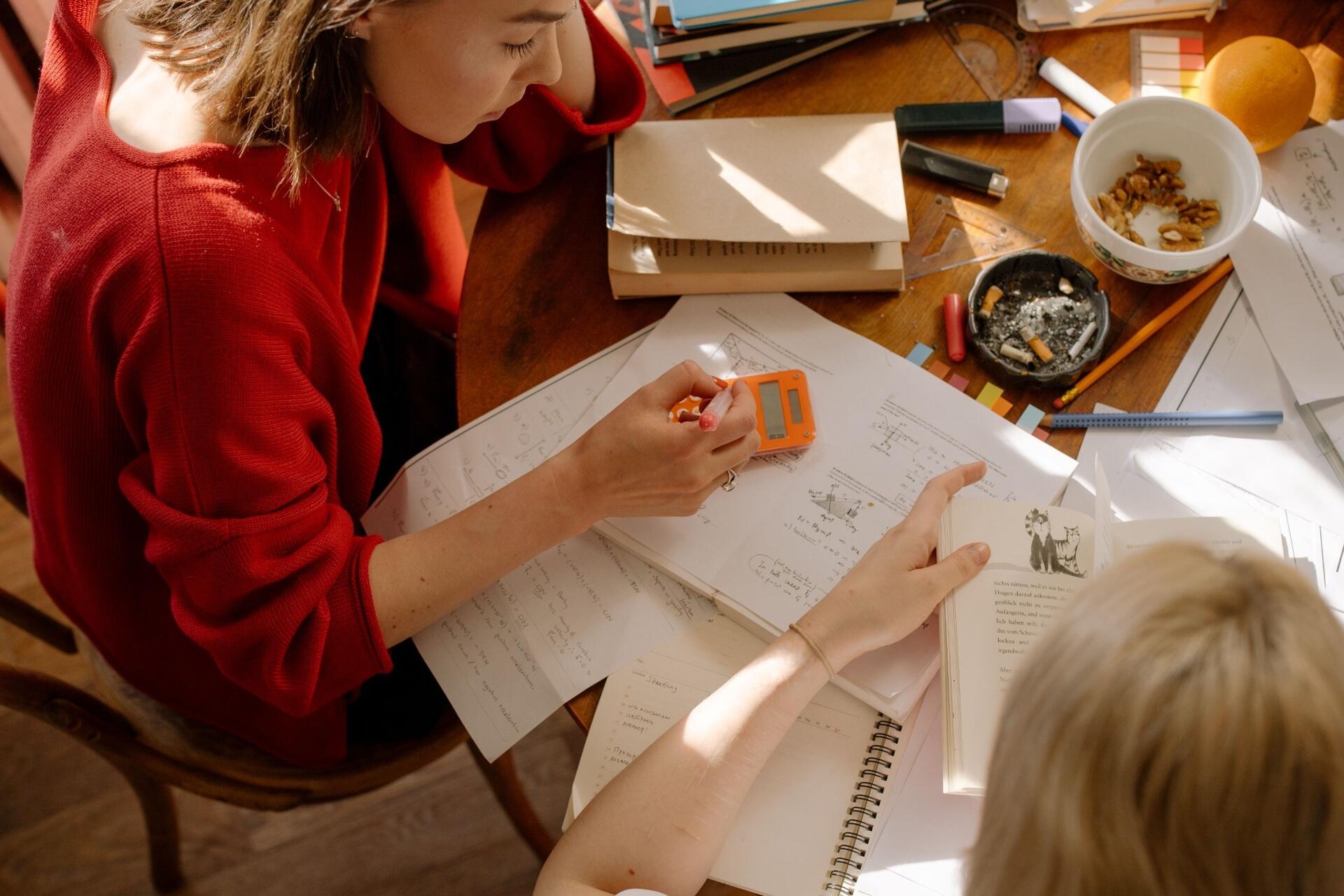 Students reviewing notes, textbooks, and worksheets together during a collaborative study session.
