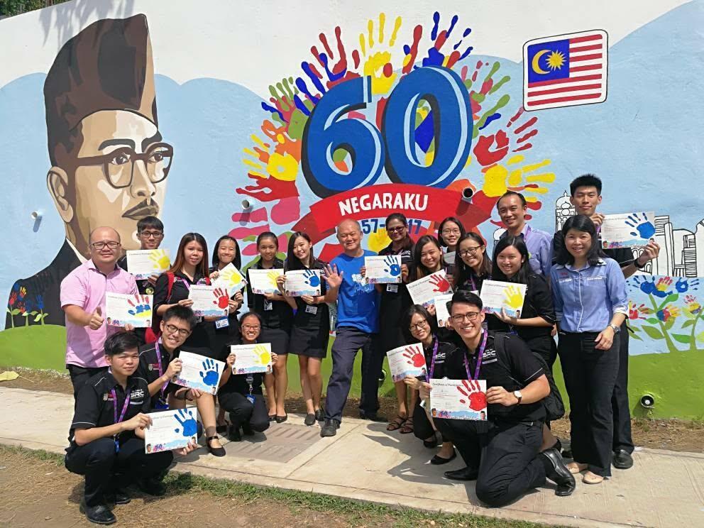 TAR UMT SRC team posing for a group photo with theircertificates after placing their palm prints on a mural wall.