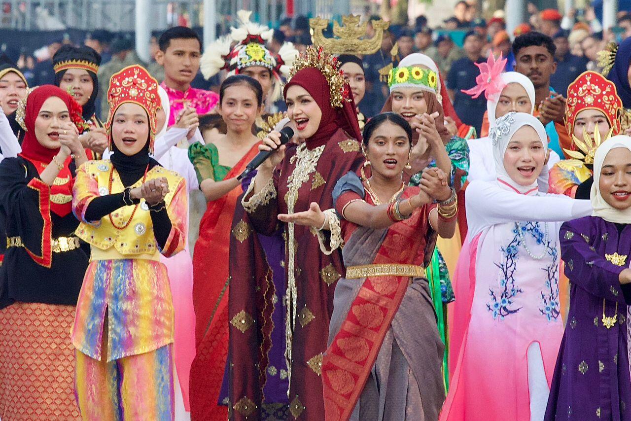 Dato- Siti Nurhaliza performing the Merdeka anthem for 2025 on Merdeka day, surrounded by background dancers in ethnic outfits.