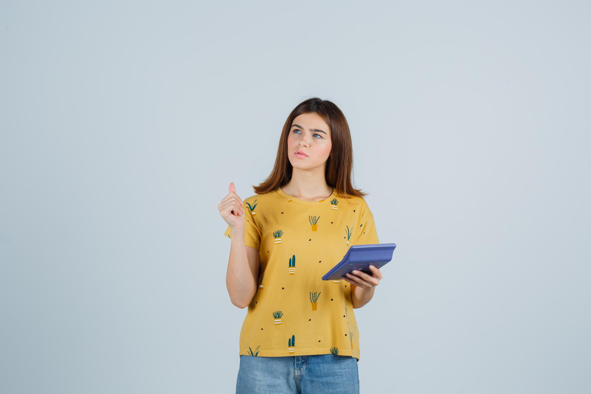 Young woman holding a tablet, smiling, and pointing upwards, suggesting an idea or inspiration.