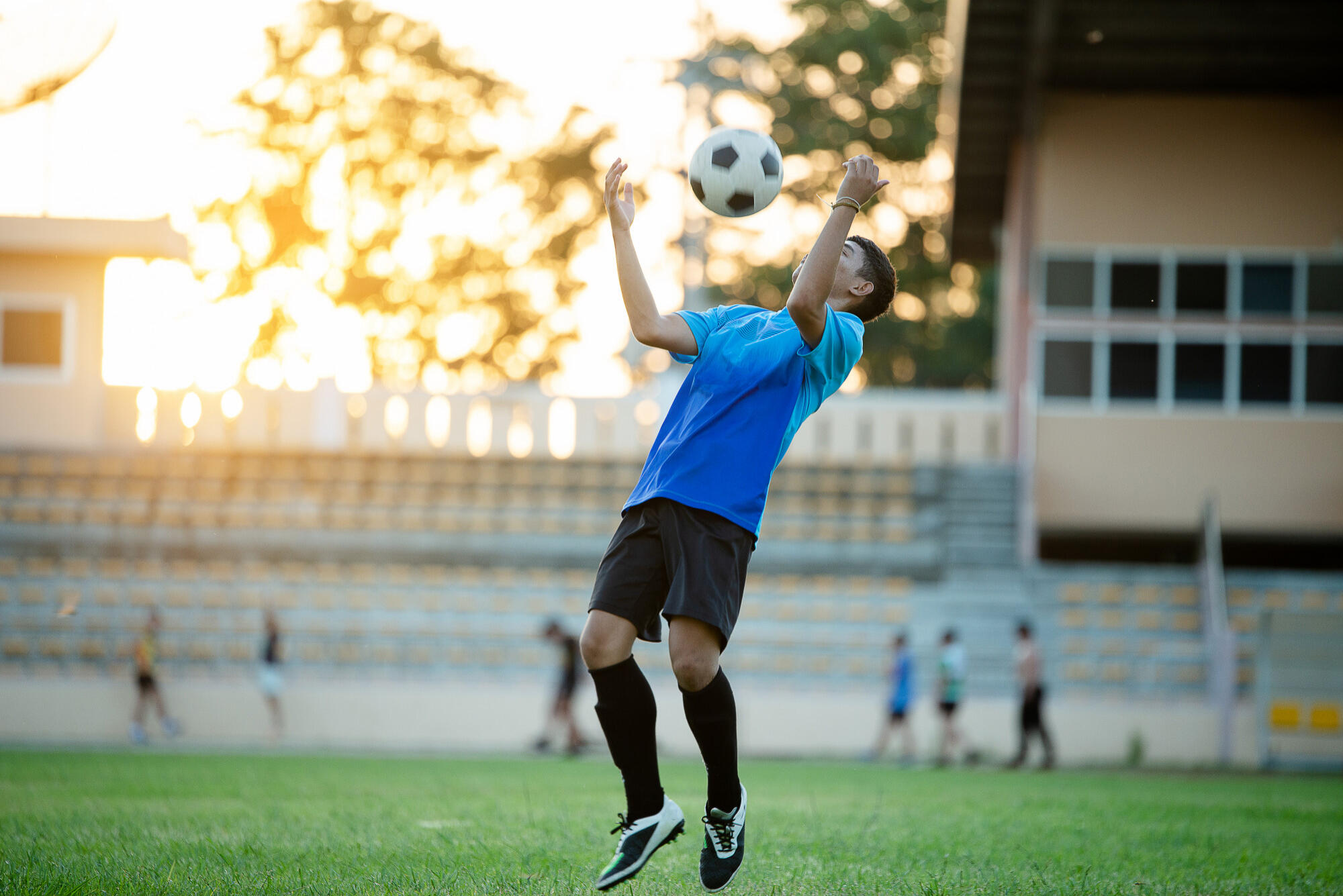 A man in athletic gear jumps to intercept a soccer ball during play.