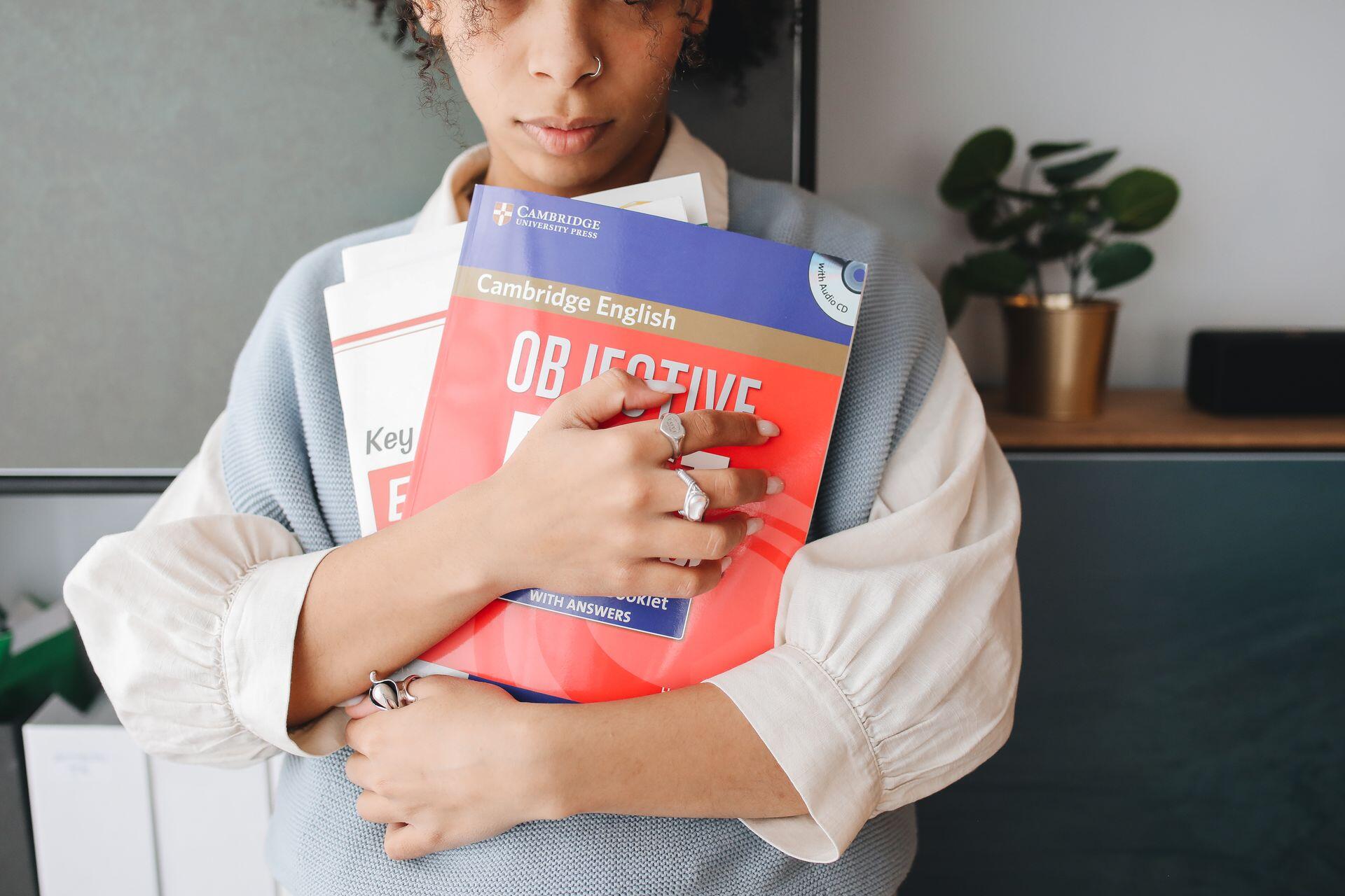 A person holding several textbooks, including