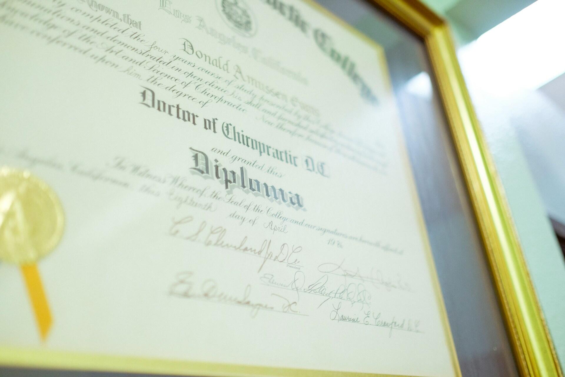 Diploma from a chiropractic college, framed and featuring a gold seal and signatures.