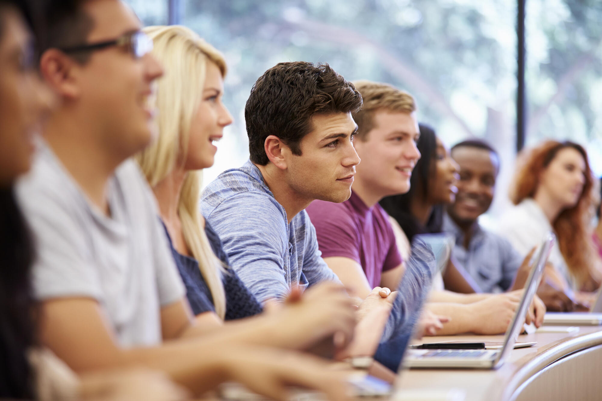Class of university students using laptops In lecture