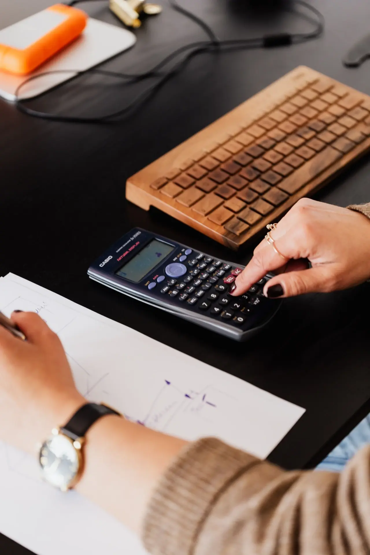 Student using a scientific calculator while practising SPM Additional Mathematics questions.