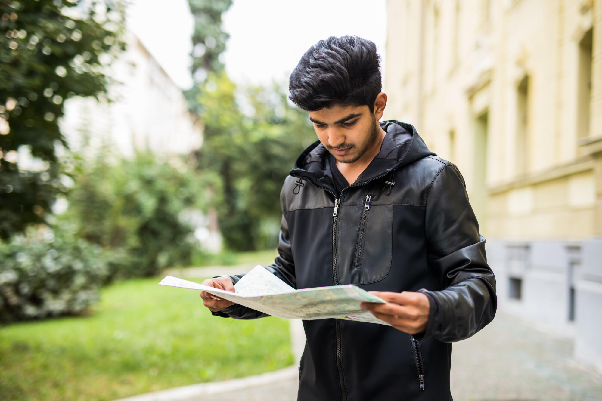 A young man studies a map, appearing focused and engaged in planning his route.
