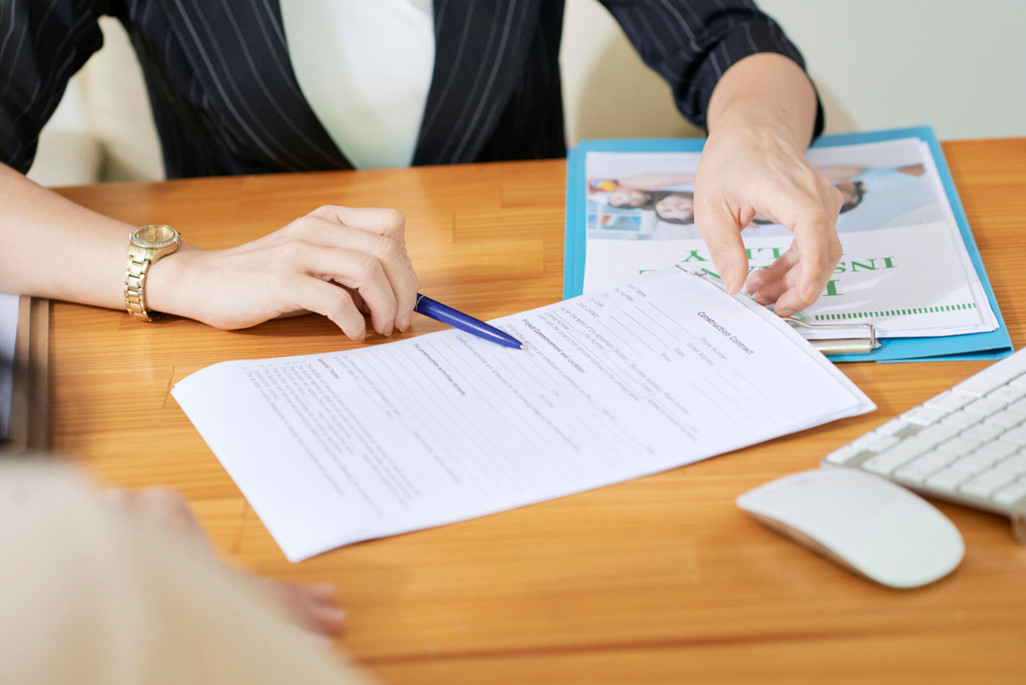 A woman signing a document with a pen, focused on the task at hand in a well-lit office setting.