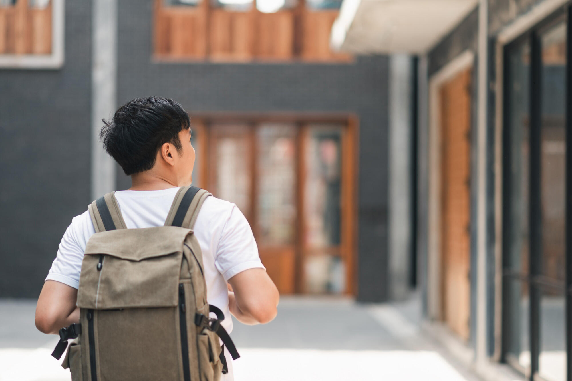 A man carrying a backpack walks along a city street, surrounded by buildings and pedestrians.