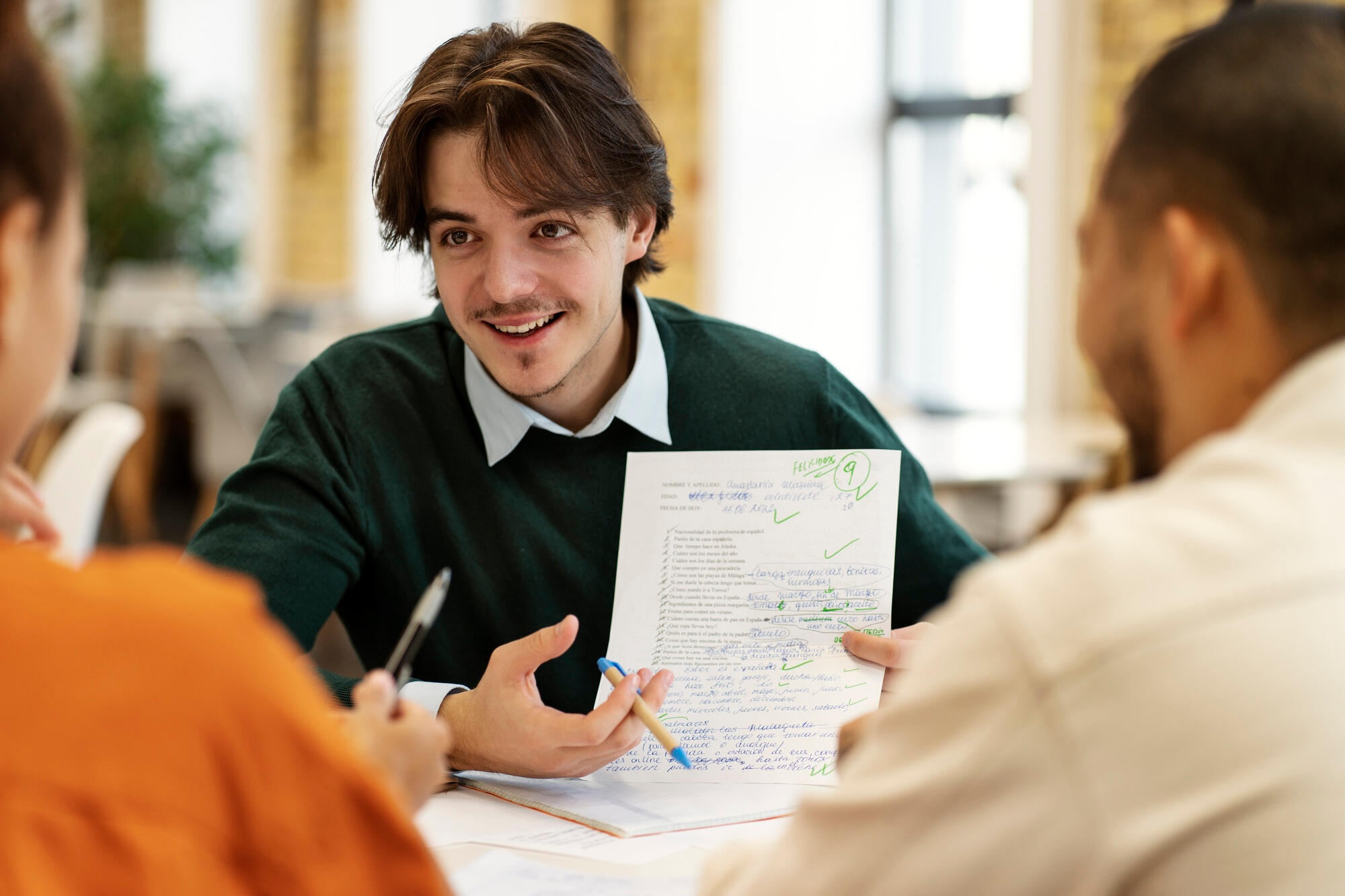 A man and two others sitting at a table, sharing ideas and interacting with each other.