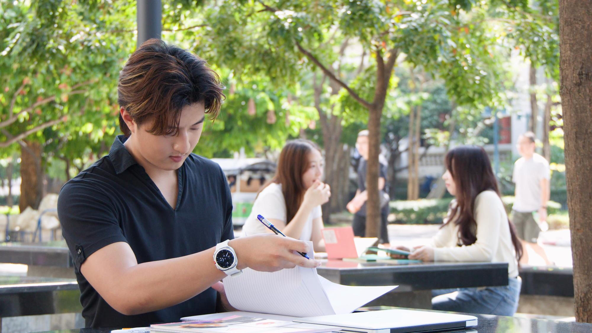 A man seated at a table, reviewing papers while holding a pen, focused on his work.