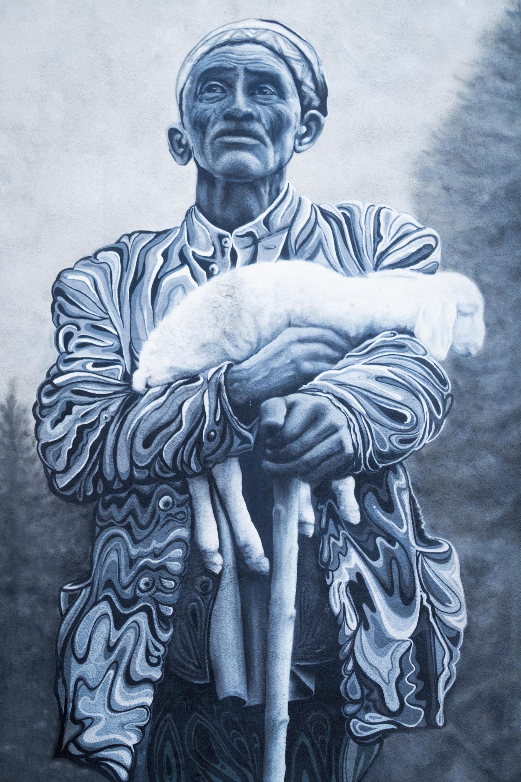 A painting of a shepherd holding his sheep.