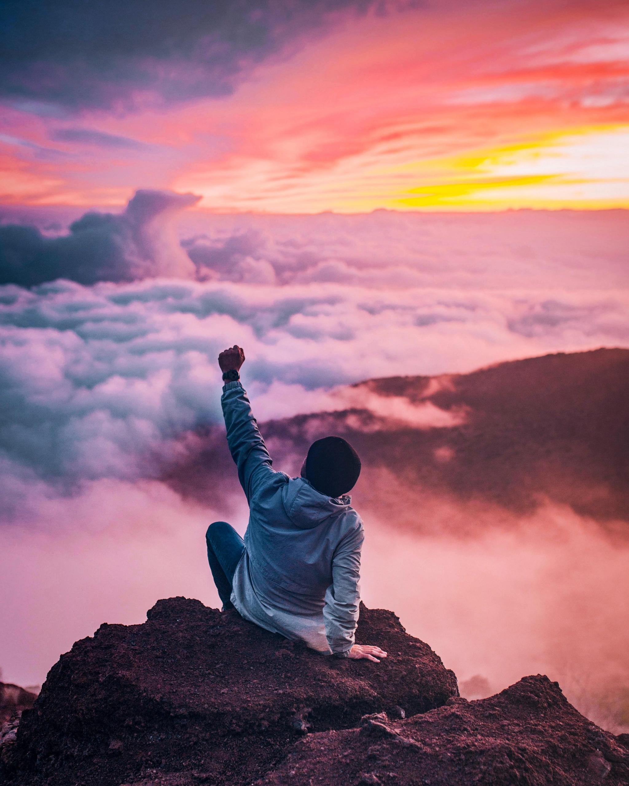 A man sitting on a rock with an outstretched arm.