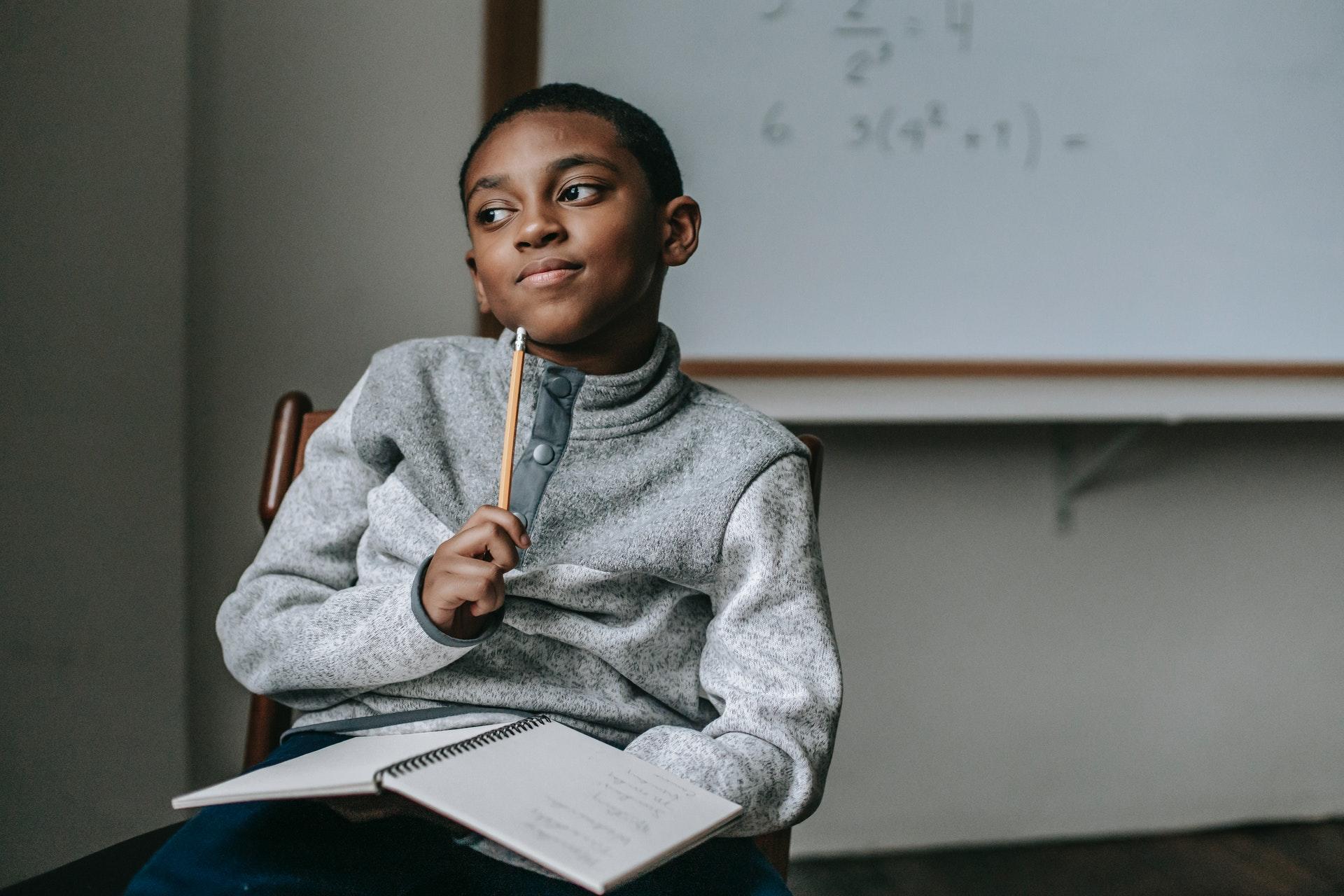 Pensive black boy smiling in a classroom