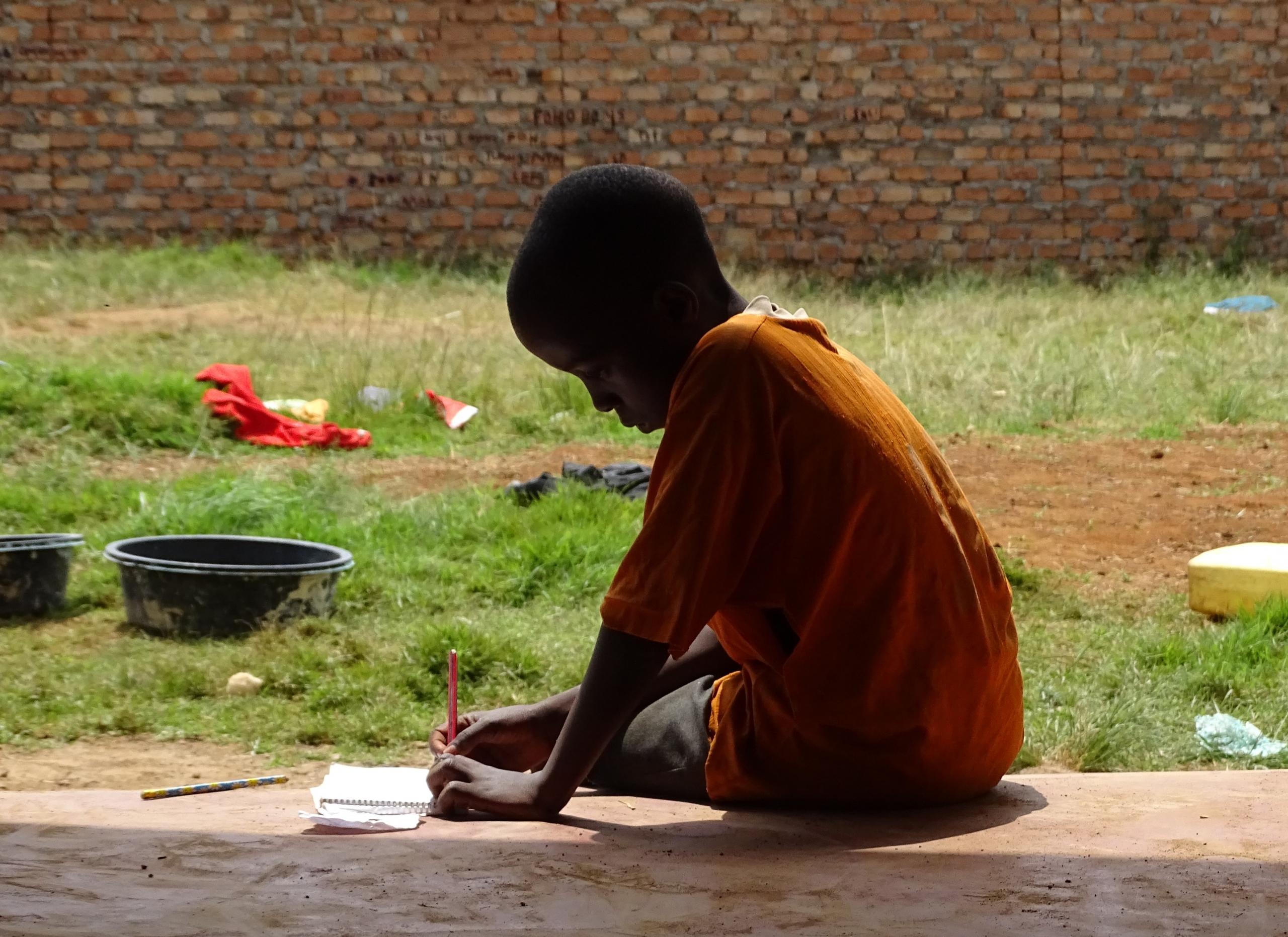 A black boy writing on a piece of paper