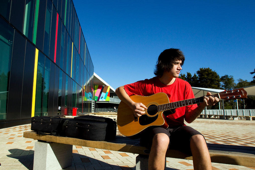 A young student playing the guitar outside