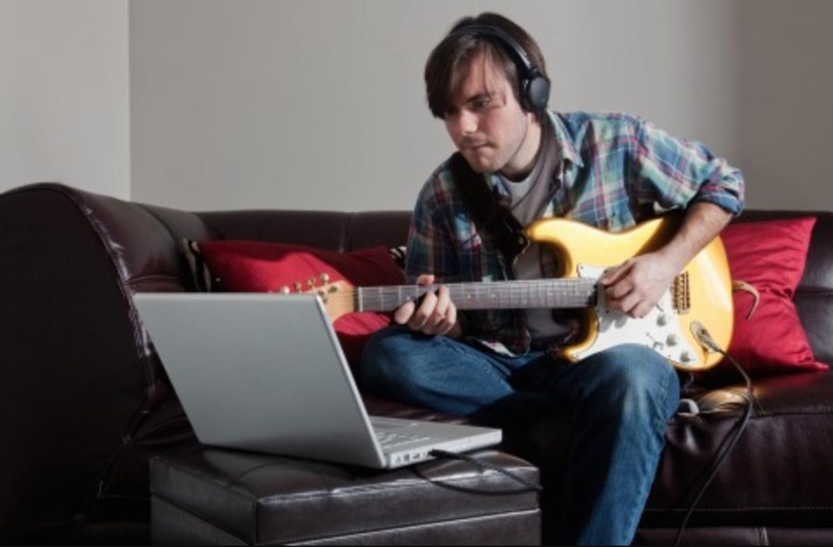 A young man learning guitar online
