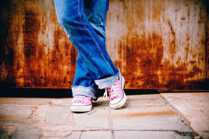 persoon met gymschoenen staat tegen hek geleund