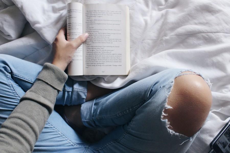 vrouw in spijkerbroek leest boek