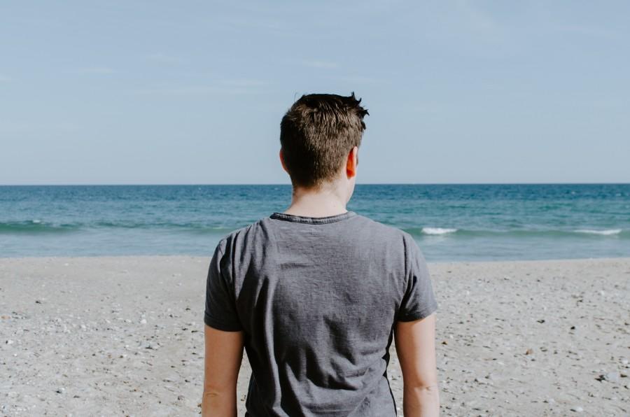 man op strand kijkt naar de zee