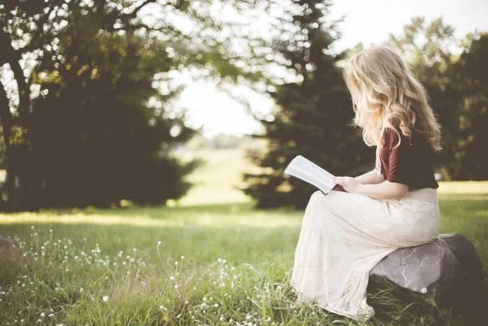 Vrouw leest boek buiten op een bankje