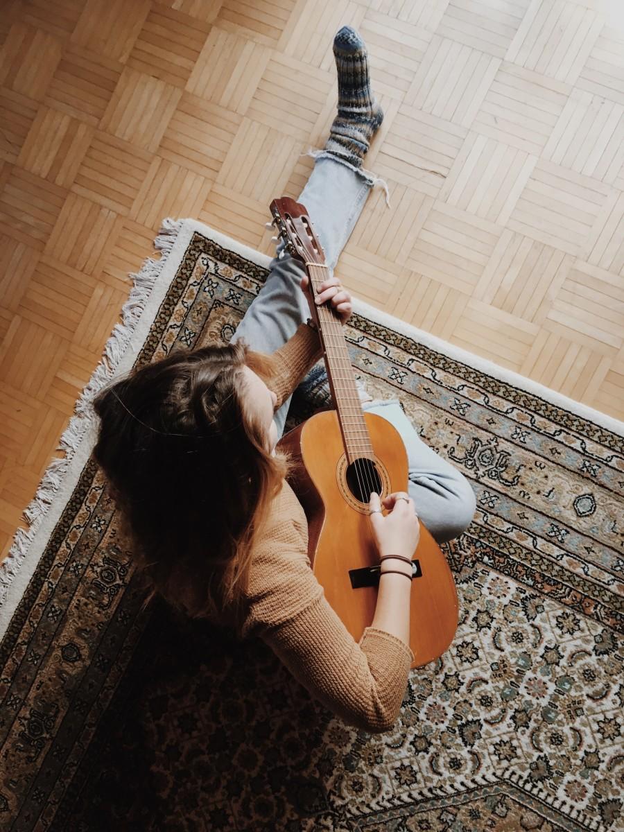 Jongere speelt gitaar op tapijt
