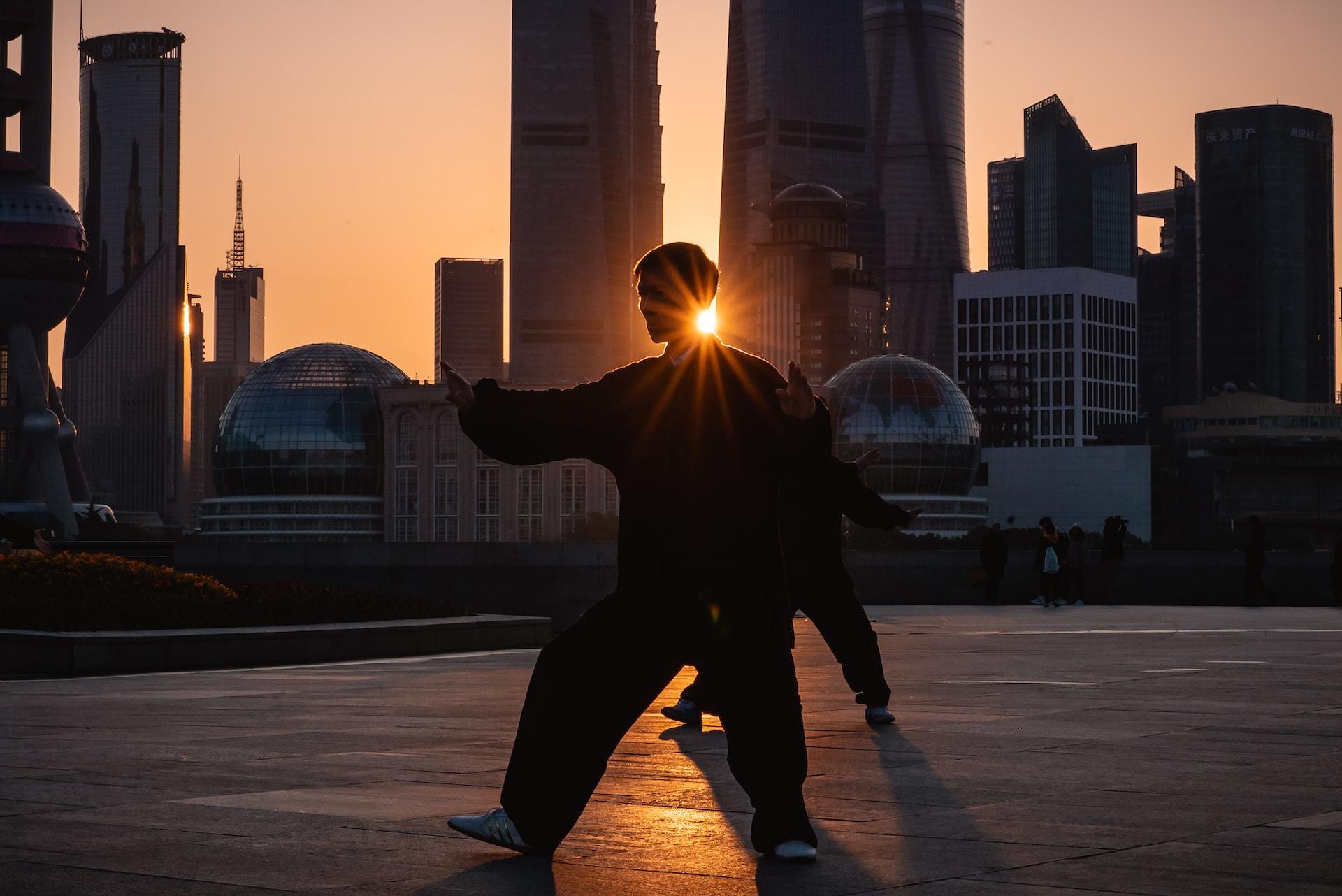 een man doet tai chi bij zonsondergang in shanghai, china