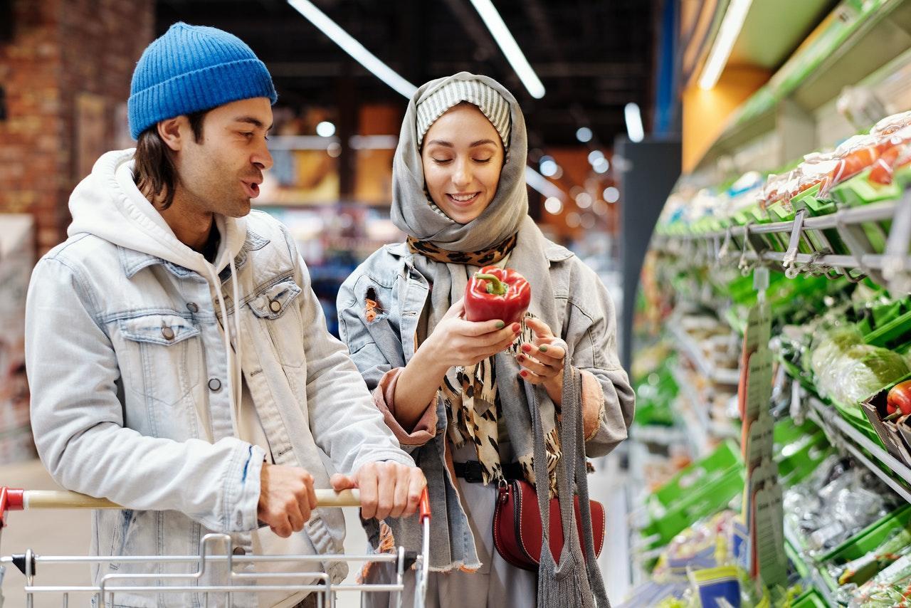 Twee mensen kopen groenten in de supermarkt.