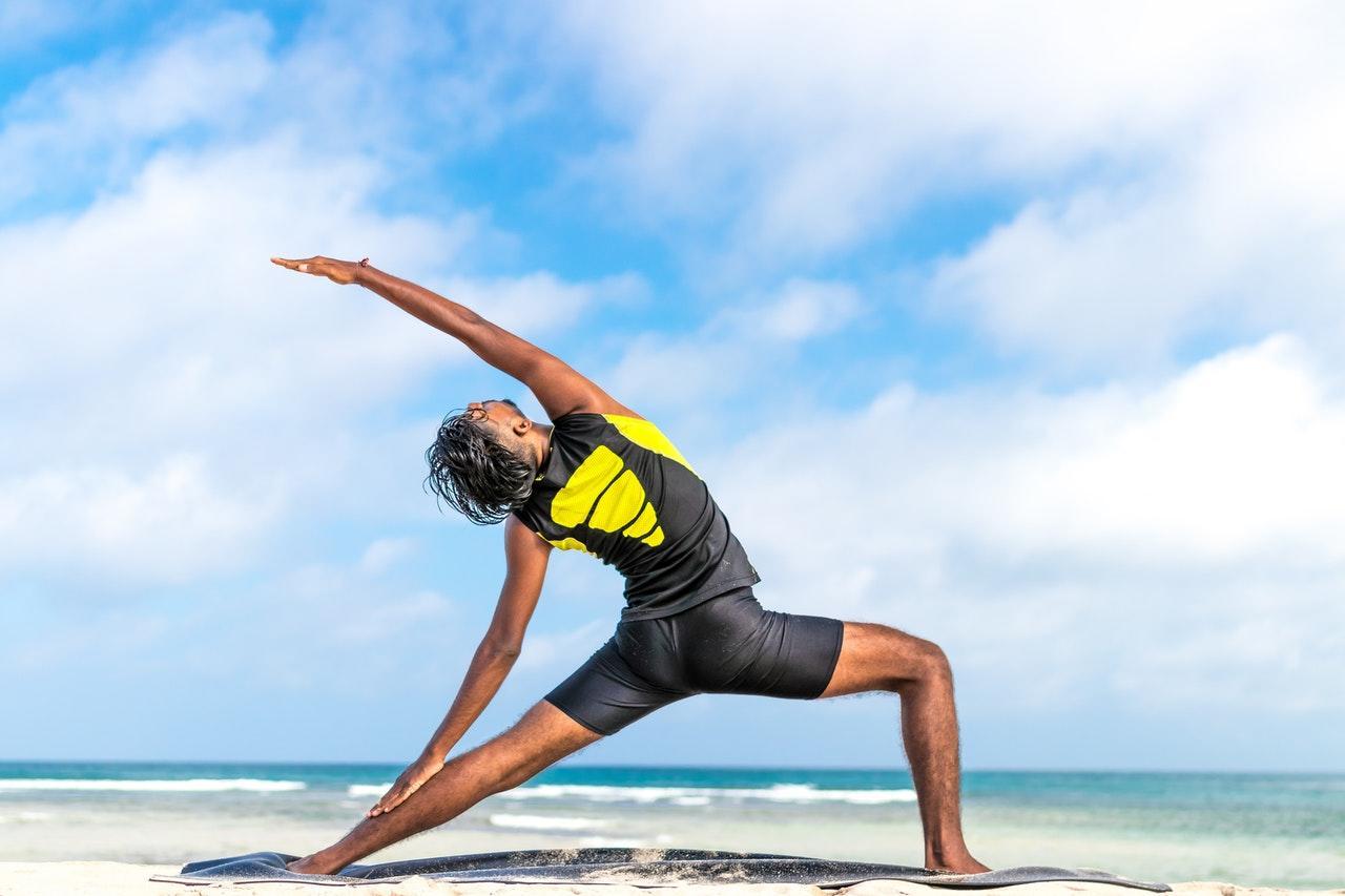 Een man in een flexibele houding op het strand.