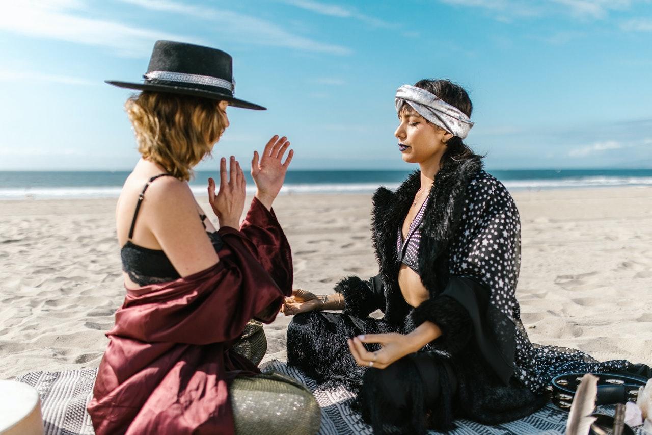 Twee vrouwen doen yoga op het strand