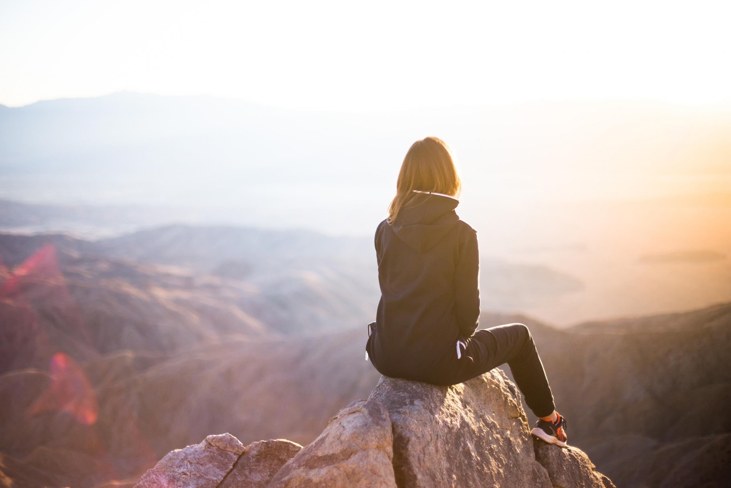 Een yogi zit op een bergtop en kijkt naar de zonsopgang