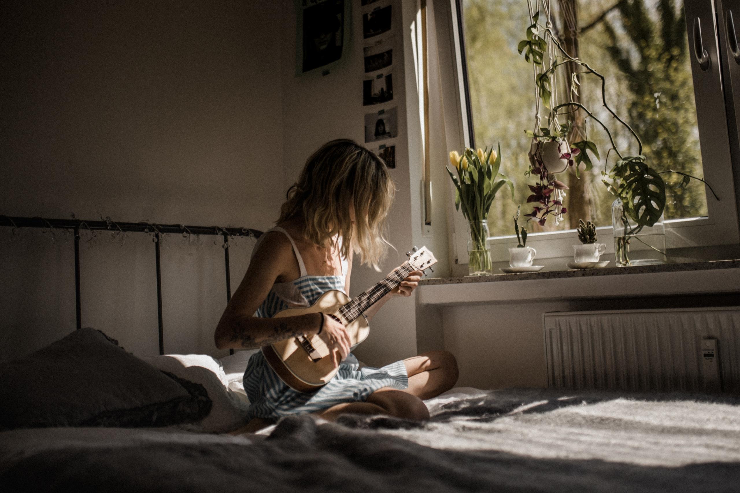 Persoon op bed speelt gitaar